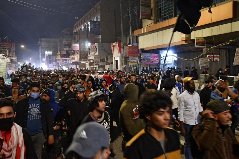 Anti-government protesters carry a mock coffin during a demonstration calling for the resignation of governor Nazem al-Waeli, and against deteriorating public services, in Iraq's southern city of Nasiriyah in the province of Dhi Qar on February 26, 2021. Four anti-government protesters were killed in clashes with Iraqi security forces in Nasiriyah, medics said, the deadliest day in a week of violence in the southern city. Protesters have defied a second wave of coronavirus infections and renewed lockdown measures to vent their anger at the government over poor public services. / AFP / Asaad NIAZI
