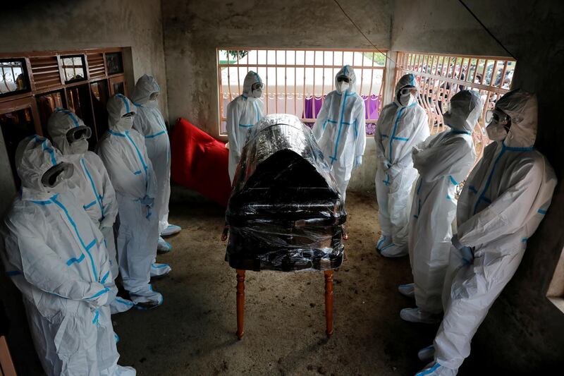 Men dressed in protective suits stand around the coffin of Kenyan doctor Daniel Alushula who died of coronavirus disease (COVID-19), during his funeral in the village of Khumusalaba, in Kakamega county, Kenya. REUTERS
