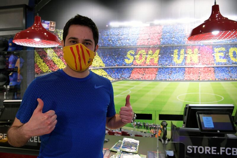 A supporter poses wearing a mask bearing the logo of FC Barcelona after buying it at the FC Barcelona store. AFP