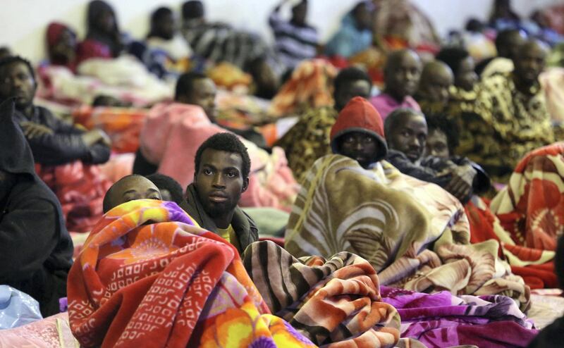 A picture taken on December 11, 2017 shows African migrants sitting and lying in a shelter at the Tariq Al-Matar migrant detention centre on the outskirts of the Libyan capital Tripoli. / AFP PHOTO / Mahmud TURKIA