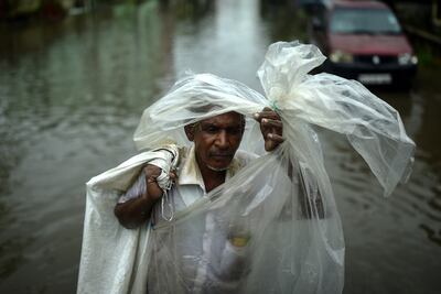 A man wraps himself in a makeshift plastic cover as he crosses a waterlogged street following heavy rains in Chennai. EPA