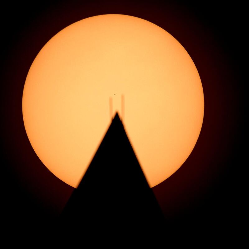 A handout photo made available by NASA, showing the the planet Mercury seen in silhouette, centre, as it transits across the face of the Sun, behind the Washington Monument. Mercury's last transit was in 2016. The next transit will not happen again until 2032.  EPA