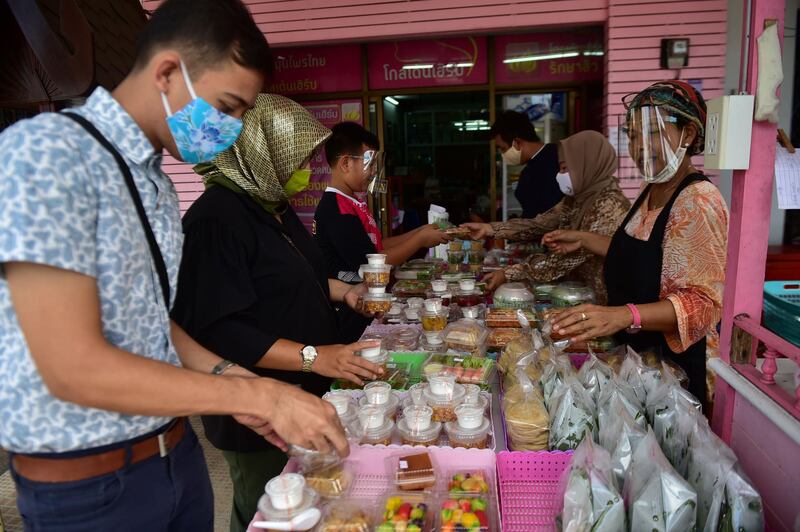 People wearing face masks  buy food at a market in Thailand's southern Narathiwat province.  AFP