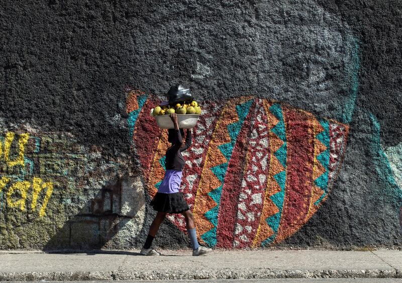 A fruit vendor walks in front of a mural in Port-au-Prince, Haiti. EPA