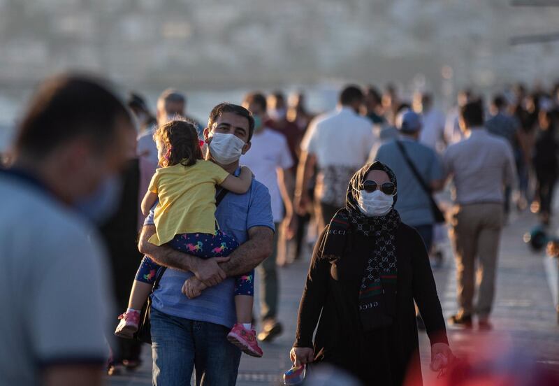 People wearing face masks walk near the Bosphorus at sunset in Istanbul, Turkey.  EPA