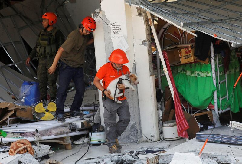 A rescuer carries a search dog as they try to reach survivors. Reuters