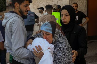 A Palestinian woman kisses the sheet-covered body of a child killed during an Israeli air strike outside al-Aqsa hospital, in Gaza Strip. AP