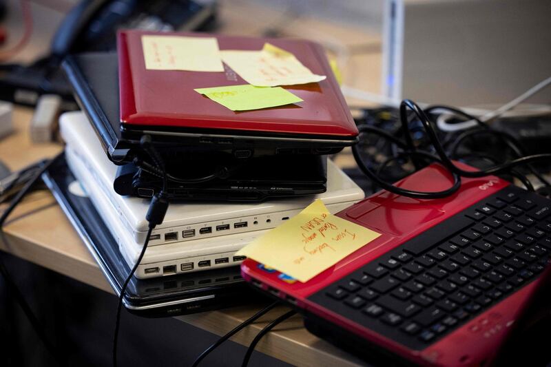 Donated computers with notes marking their faults are seen on a workbench at Catbytes. In a community centre in London, volunteers take screwdrivers to piles of laptops and check they are operating well. The computers donated by members of the public will go to children whose families do not have the laptops they need to take part in lessons online. AFP