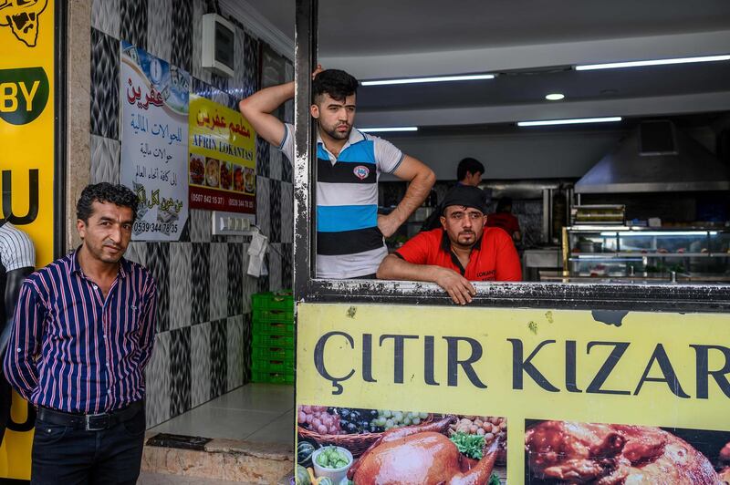 Employers who work for a Syrian restaurant named Afrin Restaurant stand in front of a damaged restaurant in Istanbul's working-class district of Kucukcekmece on July 5, 2019.  The most recent violence against Syrians in Kucukcekmece 10 days ago has raised fears of an escalation in an already volatile climate. Xenophobic language has been unleashed, particularly during the campaigns for local elections. Turkey is home to the largest number of refugees in the world, having welcomed over 3.5 million Syrians -- including 500,000 in Istanbul -- who were forced to flee their country. / AFP / BULENT KILIC
