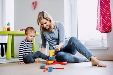 Smiling mother and toddler son playing with building blocks at home. Getty Images