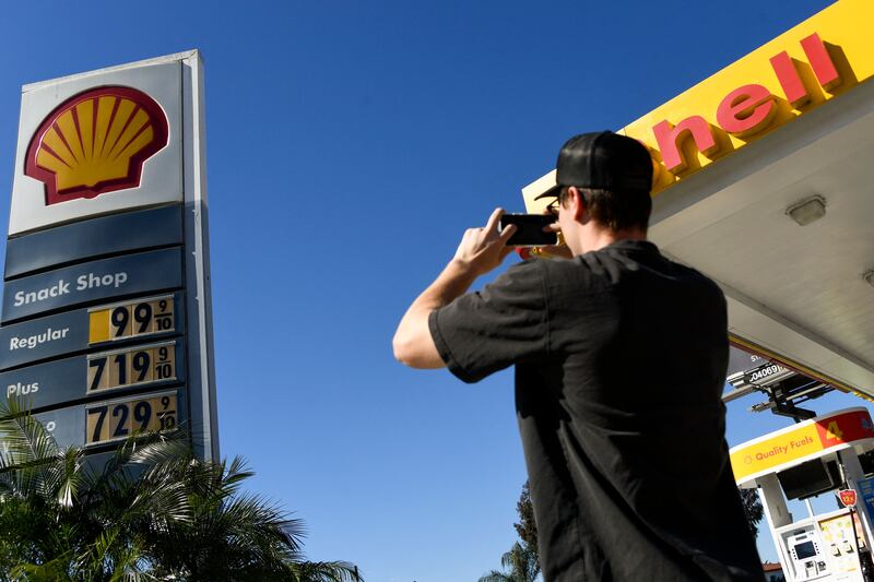 A person takes photographs of petrol prices at a Shell station in Los Angeles, California. AFP