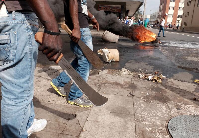 Men armed with machetes make their way to street clashes with police in Durban, South Africa. Tebogo Letsie / AP Photo
