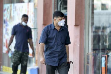 People wear face masks to guard against Covid-19 in Deira, Dubai. Authorities have handed out more fines to those working without face coverings. Pawan Singh / The National