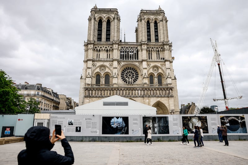 A man takes a photograph of the Notre-Dame Cathedral with its giant crane in Paris, France, 15 April 2024, ahead of its reopening scheduled for December 2024.