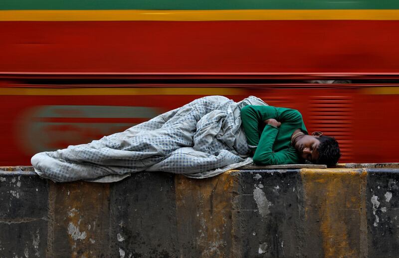 A homeless man sleeps on a road divider as a passenger bus passes by at a slum in Mumbai, India. Danish Siddiqui/Reuters