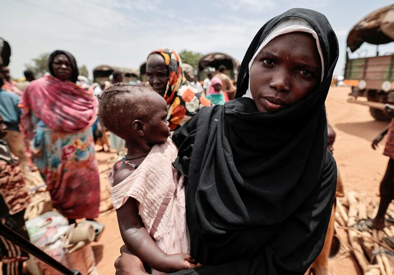 A Sudanese woman carries her daughter after being relocated from makeshift shelters to a refugee camp in Ourang, Chad.