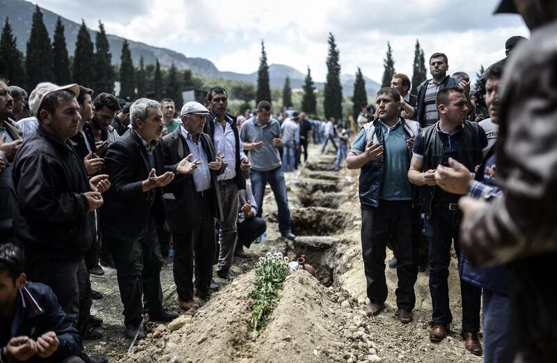 People mourn near graves during a funeral ceremony in the western town of Soma in the Manisa province on May 15, 2014 after the country's worst mining accident which killed at least 282 workers and left scores trapped underground.  Bulent Kilic/AFP Photo

