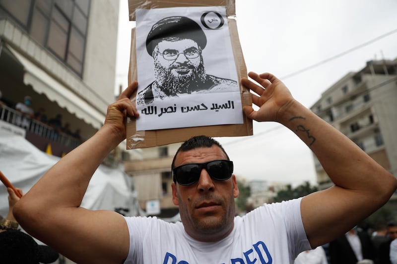 A Hezbollah supporter holds a placard depicting its leader Sayyed Hassan Nasrallah, during a protest against U.S. interference in Lebanon's affairs, near the U.S. embassy, in Aukar northeast of Beirut, Lebanon, Friday, July 10, 2020. The Arabic words on the placard read:"Sayyed Hassan Nasrallah." (AP Photo/Hussein Malla)