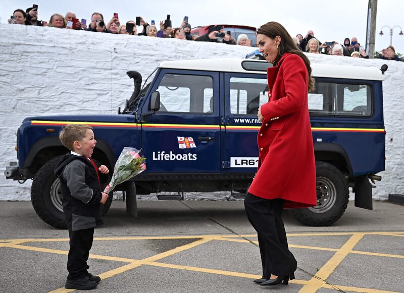 Britain's Catherine, Princess of Wales reacts as she is presented with a posy of flowers by four-year-old Theo Crompton during a visit to the RNLI (Royal National Lifeboat Institution) Holyhead Lifeboat Station in Anglesey, north west Wales on September 27, 2022.  (Photo by Paul ELLIS  /  POOL  /  AFP)