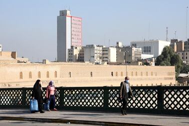 People walk past the Iraq Central Bank building in Baghdad. Iraq devalued its currency by about 23 per cent against the US dollar on December 20. Photo: EPA