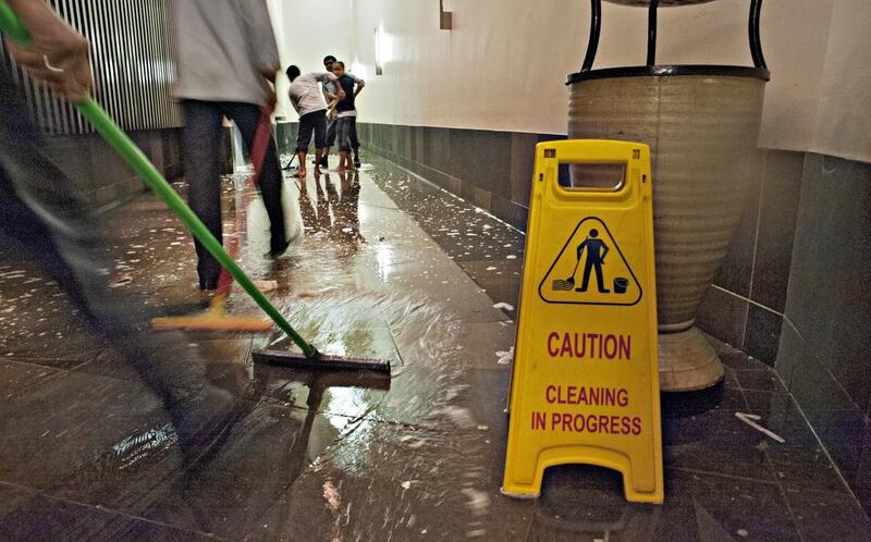 Workers push water away at Tony Roma's restaurant in Ibn Battuta Mall. Jeff Topping for The National