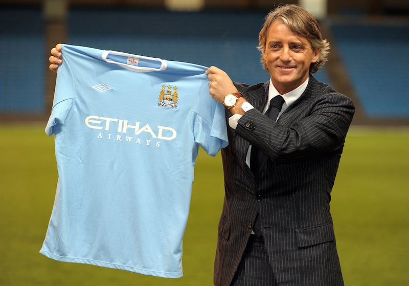 New Manchester City manager Roberto Mancini poses for photographers at the City of Manchester stadium in Manchester, north-west England on December 21, 2009, Mancini takes over from the recently departed Mark Hughes. AFP PHOTO/ANDREW YATES. FOR  EDITORIAL USE Additional licence required for any commercial/promotional use or use on TV or internet (except identical online version of newspaper) of Premier League/Football League photos. Tel DataCo +44 207 2981656. Do not alter/modify photo *** Local Caption ***  496235-01-08.jpg