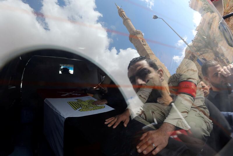 People are reflected in a vehicle window as a member of Egypt's security forces sits next to a coffin containing the body of military officer Abdulrahman Ali Mohammed, who was killed in clashes in North Sinai, during his funeral in Cairo. Reuters