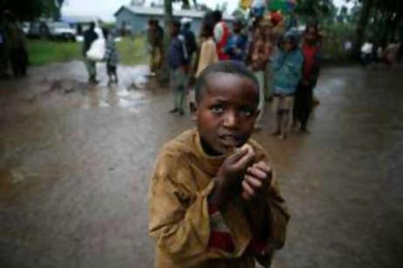 A boy shivers in the rain as drought-hit people carry sacks of maize received from an aid agency in southern Ethiopia.