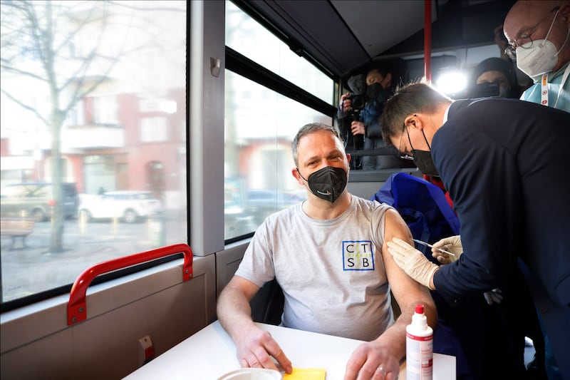 German Health Minister Karl Lauterbach, who studied medicine, vaccinates a man in the Vaccination Helps tour bus, at the project's launch in Berlin. EPA