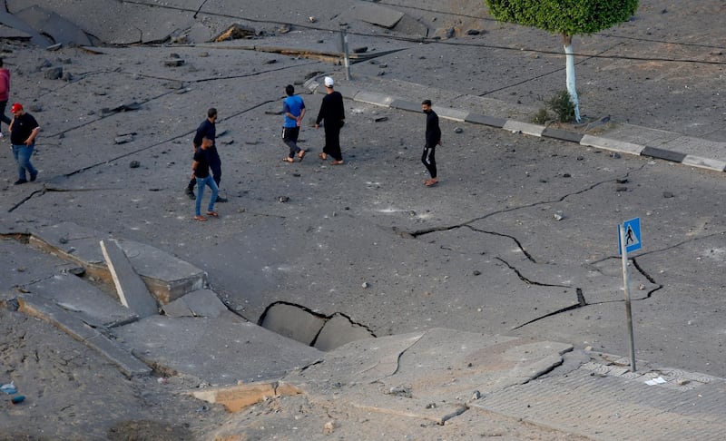 People survey the damage on a street after an Israeli air strike in Gaza City. AP