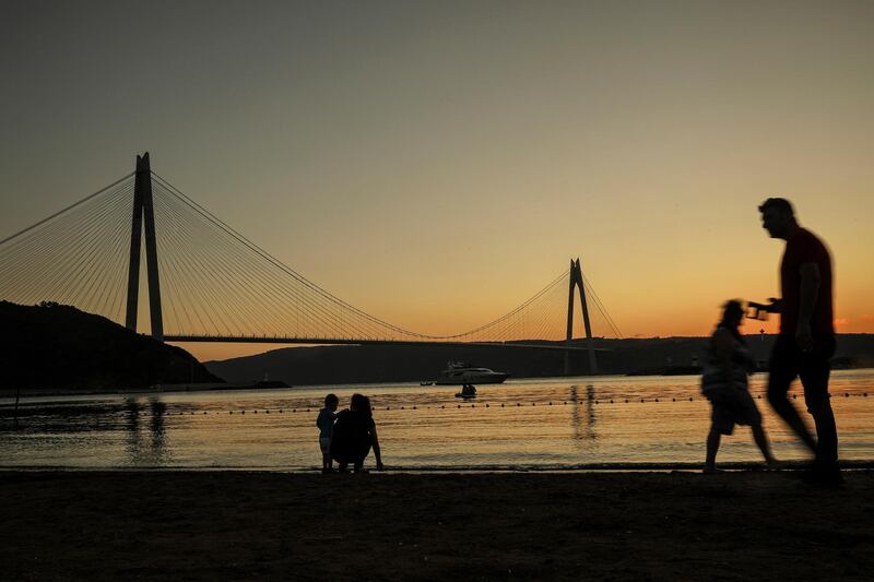 People walk on the seafront, on the Asian side of Istanbul, backdropped by the Yavuz Sultan Selim Bridge. AP