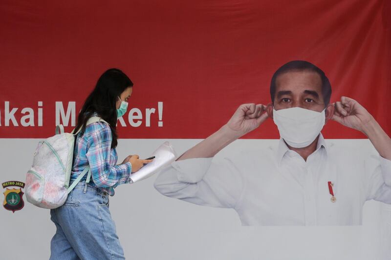 A woman walks past a banner showing Indonesia's President Joko Widodo wearing a protective face mask, in Jakarta, Indonesia. EPA