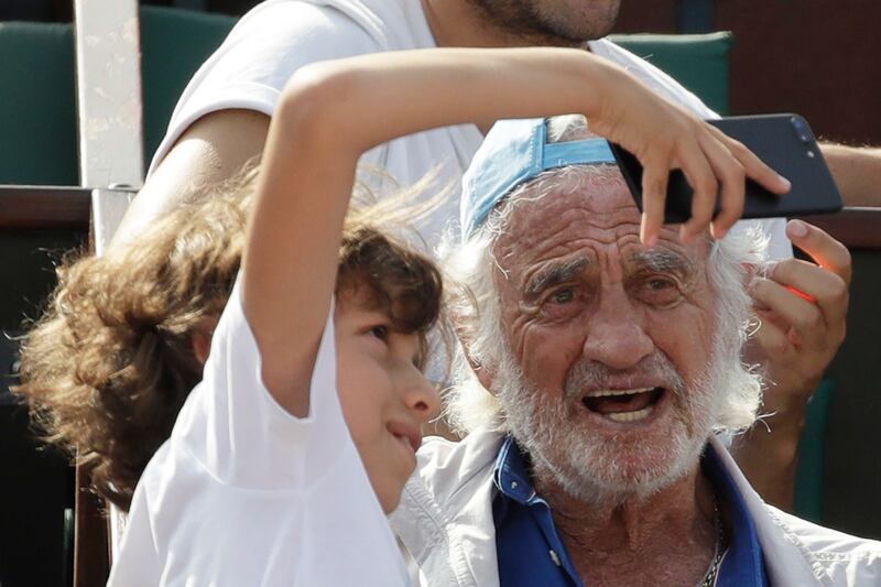 In this June 8, 2018 photo, a child takes a selfie with Jean-Paul Belmondo during the semifinal match at the French Open tennis tournament between Spain's Rafael Nadal and Argentina's Juan Martin Del Potro at the Roland Garros stadium in Paris. AP Photo