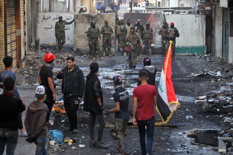 Members of the Iraqi security forces and anti-government protesters gather in front of a concrete barrier on al-Rasheed street in the capital Baghdad, during a lull in the anti-government protests.  AFP