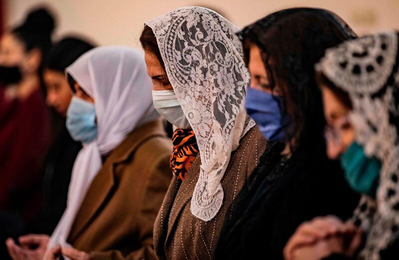 Worshippers pray during Sunday mass while wearing protective masks amid the COVID-19 pandemic at the Syriac Orthodox Church of Virgin Mary in the Kurdish-majority city of Qamishli in Syria's northeastern Hasakeh province, following the end of a lockdown.  AFP