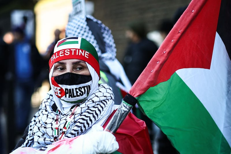 A protestor wearing a face mask and a Palestinian flag takes part in the 'National March For Palestine' in central London. AFP