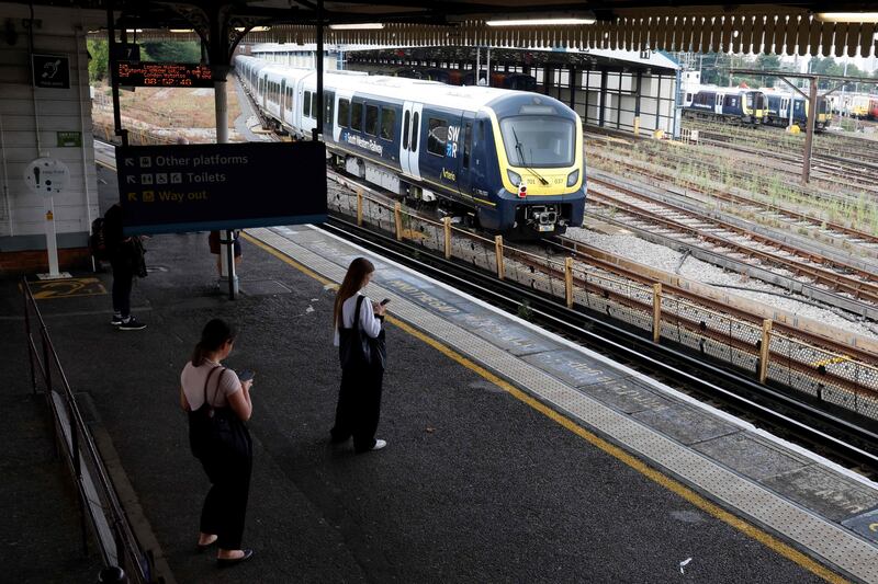 Commuters wait on a platform at Clapham Junction in London. AFP