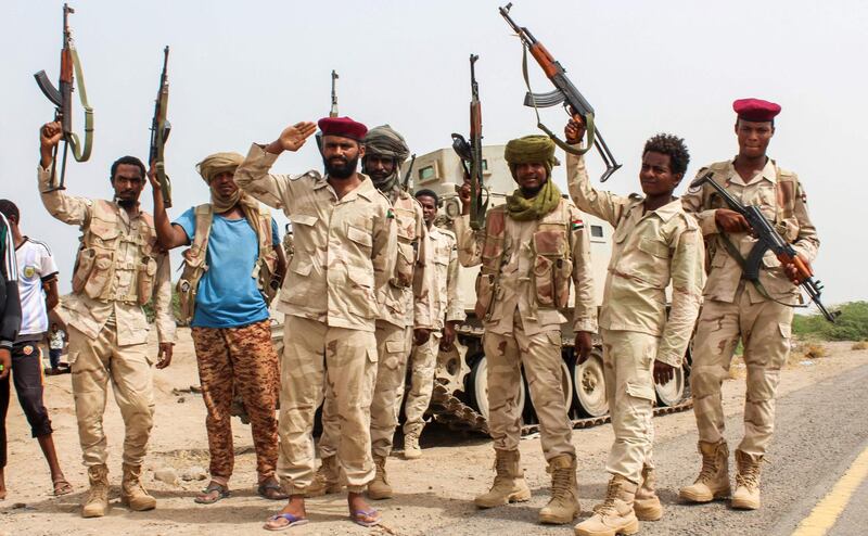 Sudanese soldiers fighting alongside Yemen's Saudi-backed pro-government forces against the Houthi rebels as they salute with their hands and firearms before a tracked vehicle on the side of a road near Al-Jah, about 50 kilometres southwest of the Red Sea port city of Hodeidah on June 22, 2018. Saleh Al-Obeidi / AFP