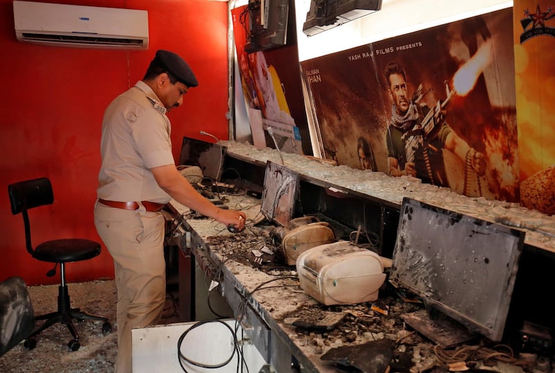 A police officer inspects the inside of a multiplex ticket counter after it was damaged by a mob on Saturday night during a protest against the release of the upcoming Bollywood movie "Padmaavat" in Ahmedabad, India January 21, 2018. REUTERS/Amit Dave