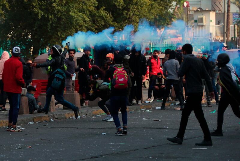 An anti-government protester throws back a tear gas canister fired by riot police during clashes with anti-government protesters in Baghdad. AP Photo