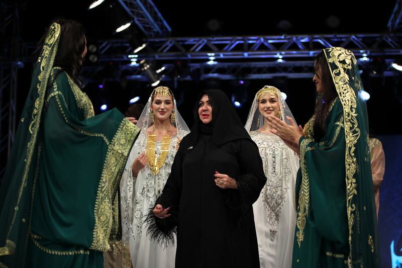 Mona Al Mansouri (C) appears with models wearing clothes she designed.
