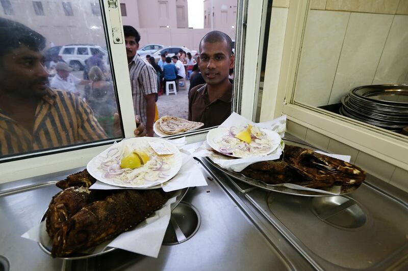 Staff collecting the fish dishes to serve customers, most of the staff are from Kerala in India.