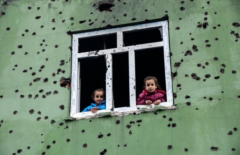 Children look out from a window of a bullet-scarred house in the Kurdish town of Silopi in south-eastern Turkey, near the border with Iraq, on January 19, 2016. AFP
