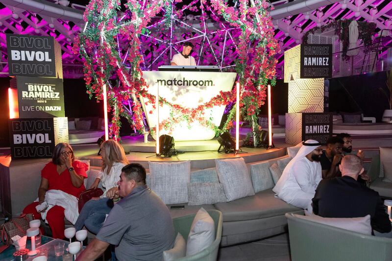 A DJ plays music as guests sit at tables during the launch party.
