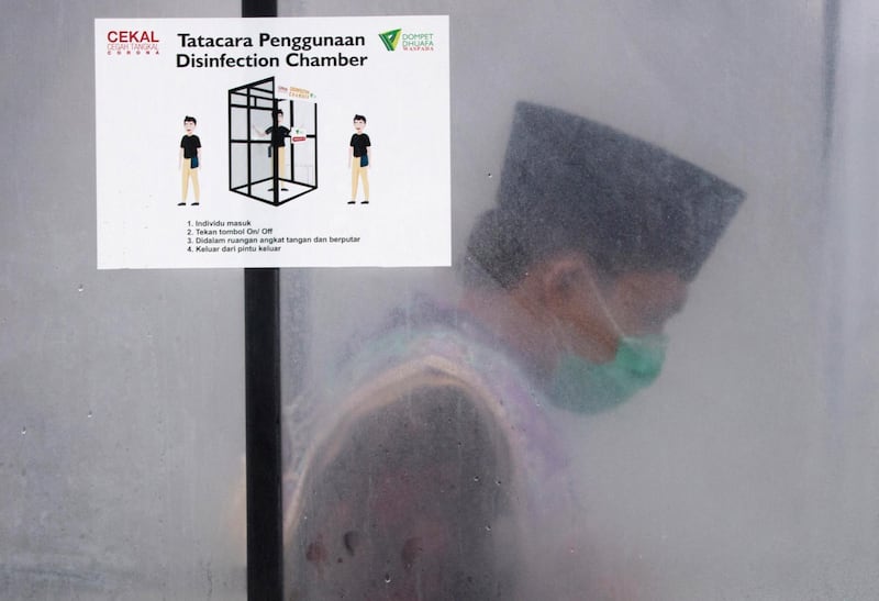A Muslim man is seen inside a disinfection chamber set up as a precaution against the new coronavirus outbreak, outside Al Mashun Grand Mosque's compound in Medan, North Sumatra, Indonesia. AP Photo