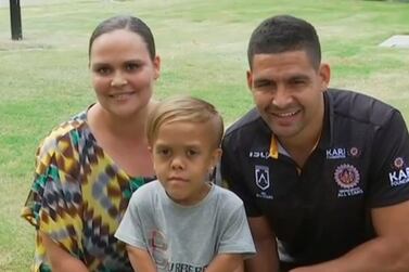 In this photo taken from video provided by Australian Broadcasting Corporation, Quaden Bayles, center, his mother, Yarraka Bayles, and Cody Walker, a professional rugby league player, pose together Friday, Feb. 21, 2020, in Gold Coast, Australia. Bayles, who has dwarfism, received an outpouring of support worldwide after his mother shared an emotional clip of him on social media. (Australian Broadcasting Corporation via AP)