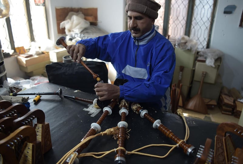 A Pakistani worker fixes a component to make a set of bagpipes at the factor. AFP.