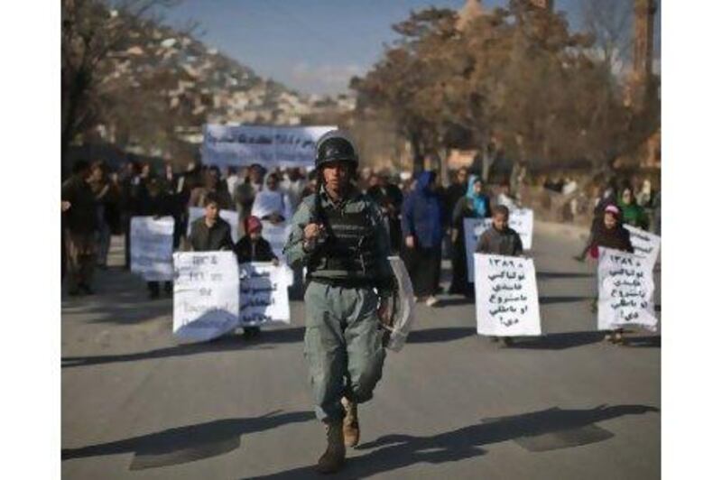 An anti-riot policeman walks ahead of marchers in a protest in Kabul yesterday by candidates in the September 18 Afghan parliamentary elections.