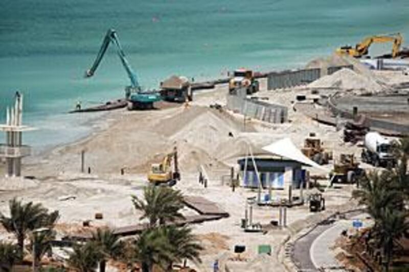 Workers from the National Marine Dredging Company are redeveloping and expanding the public beach on the Corniche.