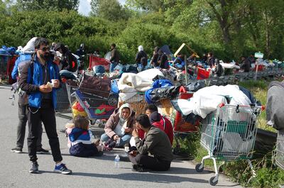 Migrants sit on the road during the evacuation of a migrant camp in northern France. AFP